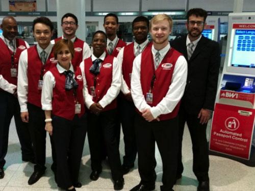 Automated Passport Control (APC) staff standing in front of APC machines.