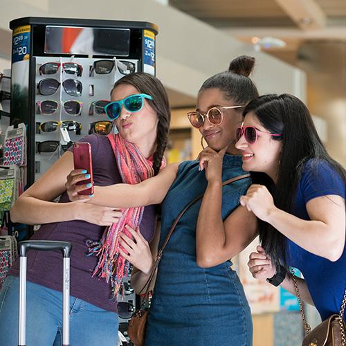 Young women trying on sunglasses at a kiosk